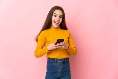 Pembe arka planda izole edilmiş küçük kız şaşırdı ve bir mesaj gönderiyor.