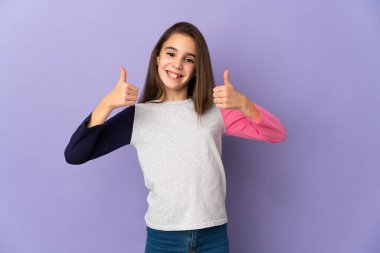 Mor arka planda izole edilmiş küçük bir kız baş parmak işareti yapıyor.