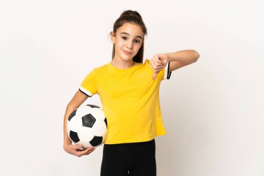 Beyaz arka planda izole edilmiş küçük futbolcu kız olumsuz ifade ile baş parmağını aşağı gösteriyor