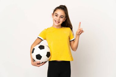 Küçük futbolcu kız beyaz arka planda izole edilmiş ve en iyinin işareti olarak parmağını kaldırıyor.
