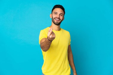 Mavi arka planda izole genç beyaz adam para jesti yapıyor