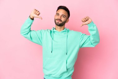 Genç beyaz adam pembe arka planda soyutlanmış gururlu ve kendini beğenmiş.