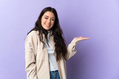 Mor arka planda izole edilmiş genç beyaz kadın bir ilan vermek için avucunun içinde hayali bir fotokopi makinesi tutuyor.