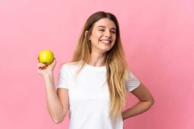 Genç sarışın kadın pembe arka planda yalnız ve mutlu bir elmayla