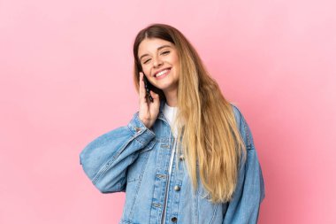 Mavi arka planda izole edilmiş genç sarışın kadın cep telefonuyla birileriyle sohbet ediyor.