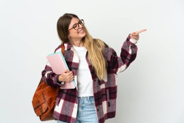 Beyaz arka planda izole edilmiş genç sarışın bir kadın parmak işareti yapıyor ve bir ürün sunuyor.