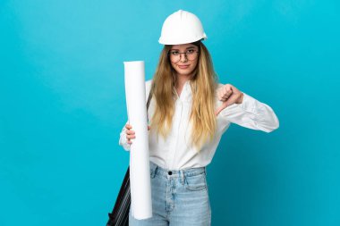 Miğferli ve elinde mavi arka planda izole edilmiş planları olan genç bir mimar kadın.
