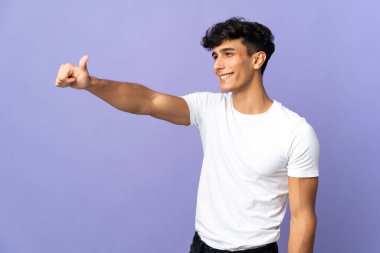 Arjantinli genç adam arka planda izole edilmiş bir şekilde baş parmak hareketi yapıyor.