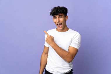 Arka planda izole edilmiş genç Arjantinli adam şaşırmış ve işaret ediyor.