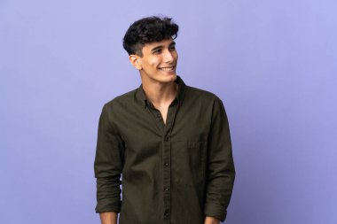 Arjantinli genç adam arka planda izole edilmiş, yana bakıyor ve gülümsüyor.