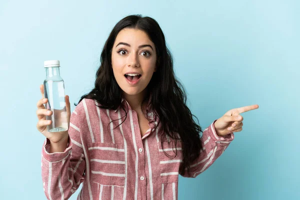 Jovem Com Uma Água Isolada Fundo Azul Surpreso Apontando Dedo — Fotografia de Stock