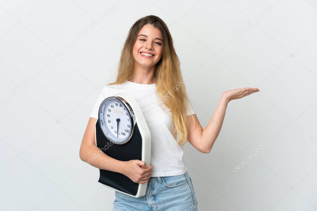 Young blonde woman isolated on white background with weighing machine