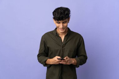 Arjantinli genç adam arka planda izole edilmiş cep telefonuyla mesaj gönderiyor.