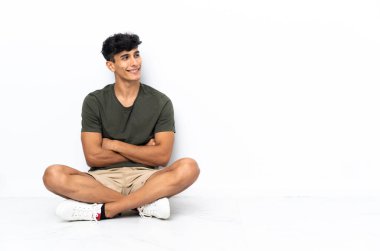 Genç Arjantinli adam yerde oturuyor.