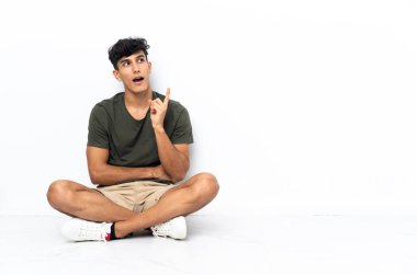 Genç Arjantinli adam yerde oturuyor ve bir fikir düşünüyor.