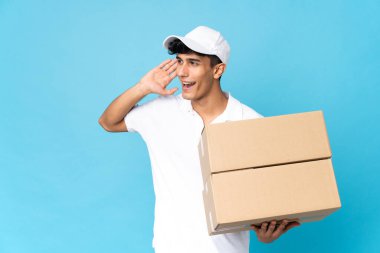 Arjantinli adam mavi arka planda izole edilmiş bir şekilde elini kulağına koyup bir şeyler dinliyor.