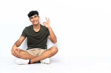 Yerde oturan genç Arjantinli adam parmaklarıyla 