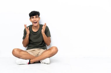 Genç Arjantinli adam yerde oturuyor ve yüzünde sürpriz bir ifade var.