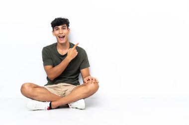 Yerde oturan genç Arjantinli şaşırmış ve işaret ediyor.