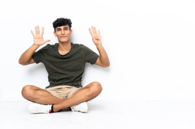 Genç Arjantinli yerde oturmuş parmaklarıyla dokuza kadar sayıyor.