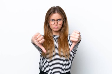 Beyaz arka planda izole edilmiş genç beyaz kadın baş parmağını iki eliyle aşağı gösteriyor.