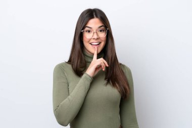 Beyaz arka planda izole edilmiş genç Brezilyalı bir kadın sessizlik işareti gösteriyor. Parmağını ağzına sokuyor.