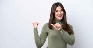 Beyaz arka planda izole edilmiş genç Brezilyalı kadın bir ürün sunmak için kenarı işaret ediyor