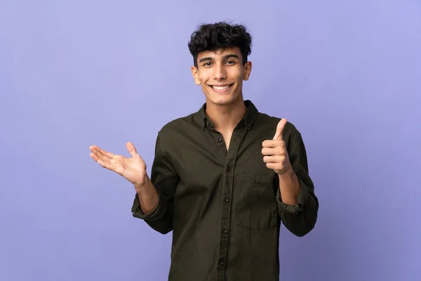 若いアルゼンチン人男性は 広告を挿入するには 手のひらの上に架空のコピースペースを保持背景に隔離され 親指アップ — ストック写真