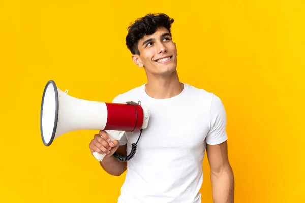 Young Argentinian Man Isolated Yellow Background Holding Megaphone Looking While — Stock Photo, Image
