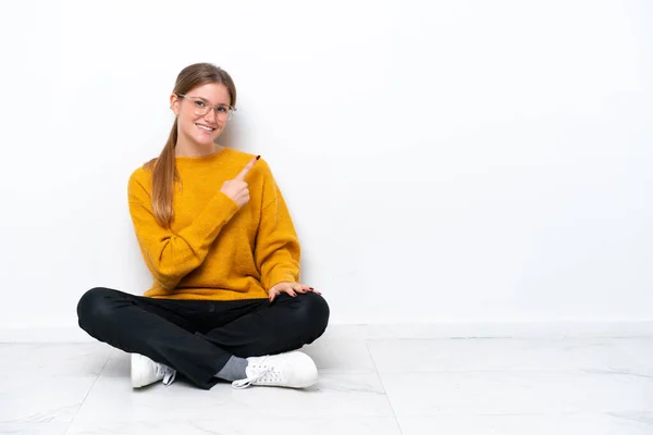 Mladé Běloška Žena Sedí Podlaze Izolované Bílém Pozadí Ukazuje Straně — Stock fotografie