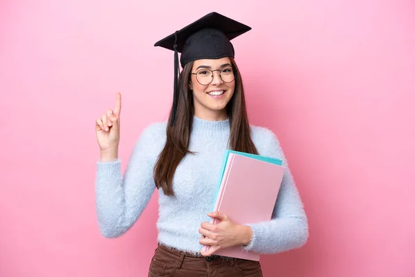 若いです学生ブラジル人女性身に着けています卒業帽子ピンクの背景に孤立素晴らしいアイデアを指摘 — ストック写真