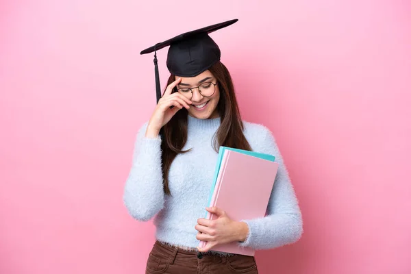 若いです学生ブラジル人女性身に着けています卒業帽子絶縁上のピンクの背景笑い — ストック写真