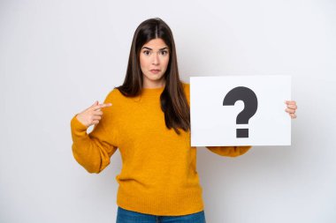 Beyaz arka planda izole edilmiş genç Brezilyalı bir kadın soru işareti sembollü bir levha tutuyor ve şaşırmış bir ifade var.