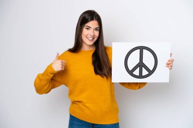 Beyaz arka planda izole edilmiş genç Brezilyalı bir kadın. Elinde başparmağıyla barış sembolü olan bir pankart tutuyor.