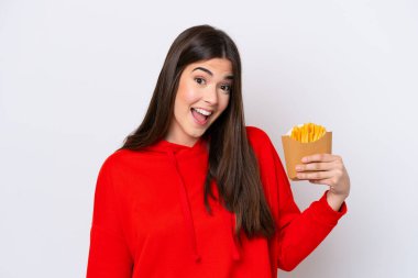Patates kızartması yakalayan Brezilyalı genç bir kadın beyaz arka planda izole edilmiş, şaşırmış ve şok olmuş bir yüz ifadesi var.