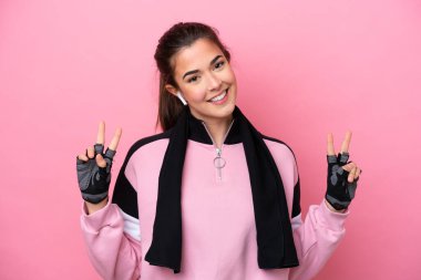 Pembe arka planda izole edilmiş genç Brezilyalı kadın iki eliyle zafer işareti gösteriyor.