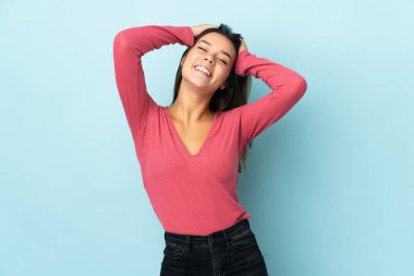 Genç kız mavi arka planda tek başına gülüyor.