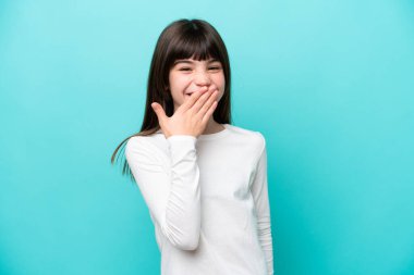 Mavi arka planda izole edilmiş küçük beyaz kız mutlu ve gülümsüyor.