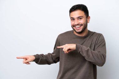 Beyaz arka planda izole edilmiş genç Brezilyalı adam şaşırmış ve işaret ediyor.
