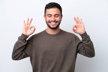 Zen pozisyonunda beyaz arka planda izole edilmiş genç Brezilyalı adam.