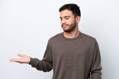 Beyaz arka planda izole edilmiş genç Brezilyalı adam, kopyalama alanını şüphe ile tutuyor