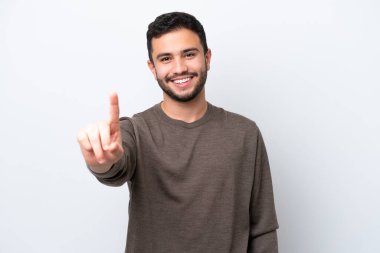 Beyaz arka planda izole edilmiş genç Brezilyalı adam parmağını kaldırıyor ve gösteriyor.