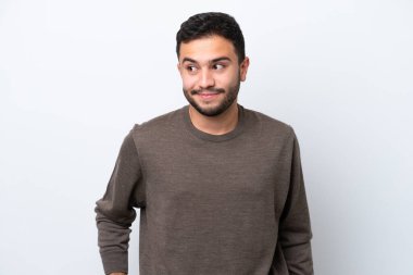 Beyaz arka planda izole edilmiş genç Brezilyalı adam şüpheli hareketler yapıyor.