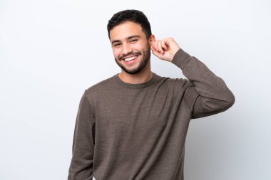 Genç Brezilyalı adam beyaz arka planda izole edilmiş gülüyor.