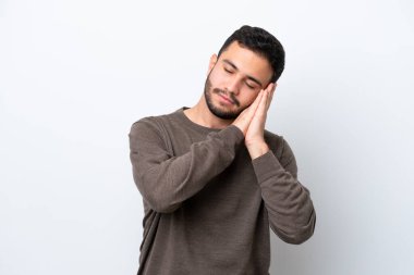 Beyaz arka planda izole edilmiş genç Brezilyalı adam uyku jesti yapıyor.