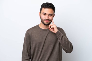 Genç Brezilyalı adam beyaz arka planda izole edilmiş ve düşünüyor.