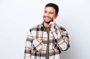 Genç Brezilyalı bir adam beyaz arka planda izole edilmiş bir şekilde bakarken bir fikir düşünüyor.