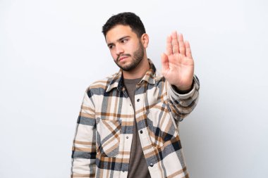 Beyaz arka planda izole edilmiş genç Brezilyalı adam dur hareketi yapıyor ve hayal kırıklığına uğruyor.