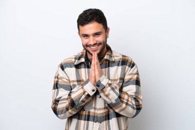 Beyaz arka planda izole edilmiş genç Brezilyalı adam avuç içlerini bir arada tutuyor. İnsan bir şey ister.