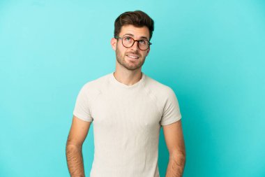 Kafkasyalı yakışıklı genç adam mavi arka planda izole edilmiş bir şekilde yukarı bakarken bir fikir düşünüyor.